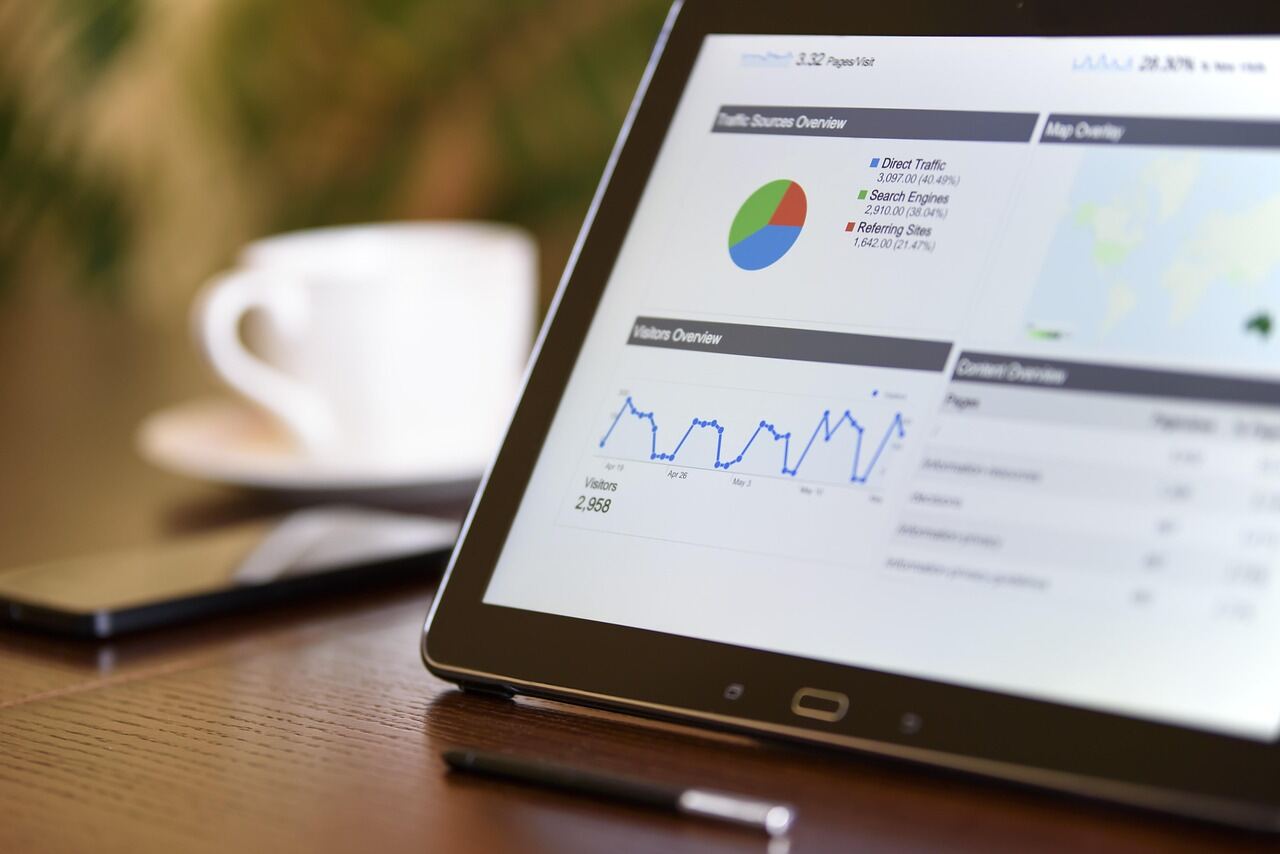 Tablet on a wooden desk showing website analytics with traffic charts and a visitors overview graph