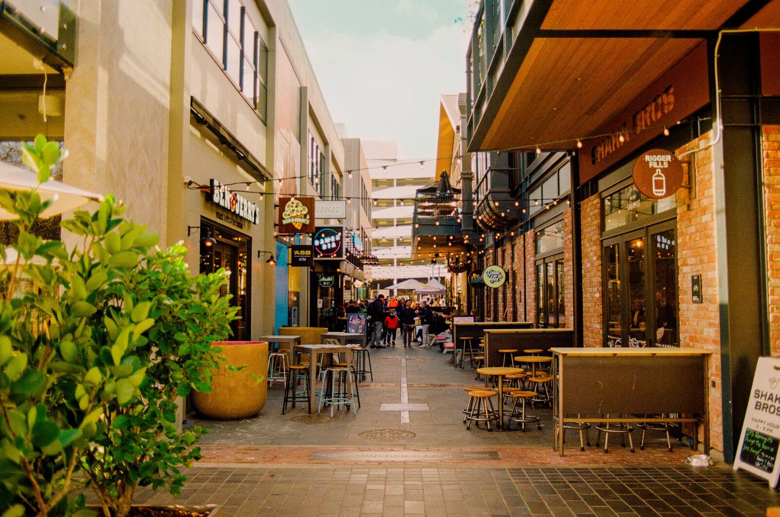 A lively Christchurch laneway lined with cafes, bars, and small businesses with outdoor seating and string lights