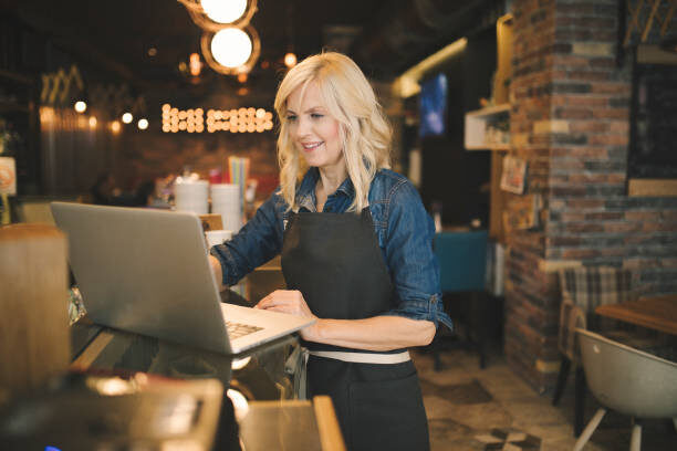 Small business owner working on a laptop in their café