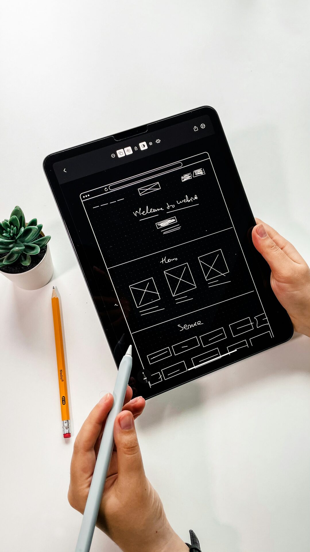 Designer sketching a website wireframe on a tablet — welcome section, hero, and service blocks mapped out as part of a clearer, mobile-friendly website redesign for NZ small businesses